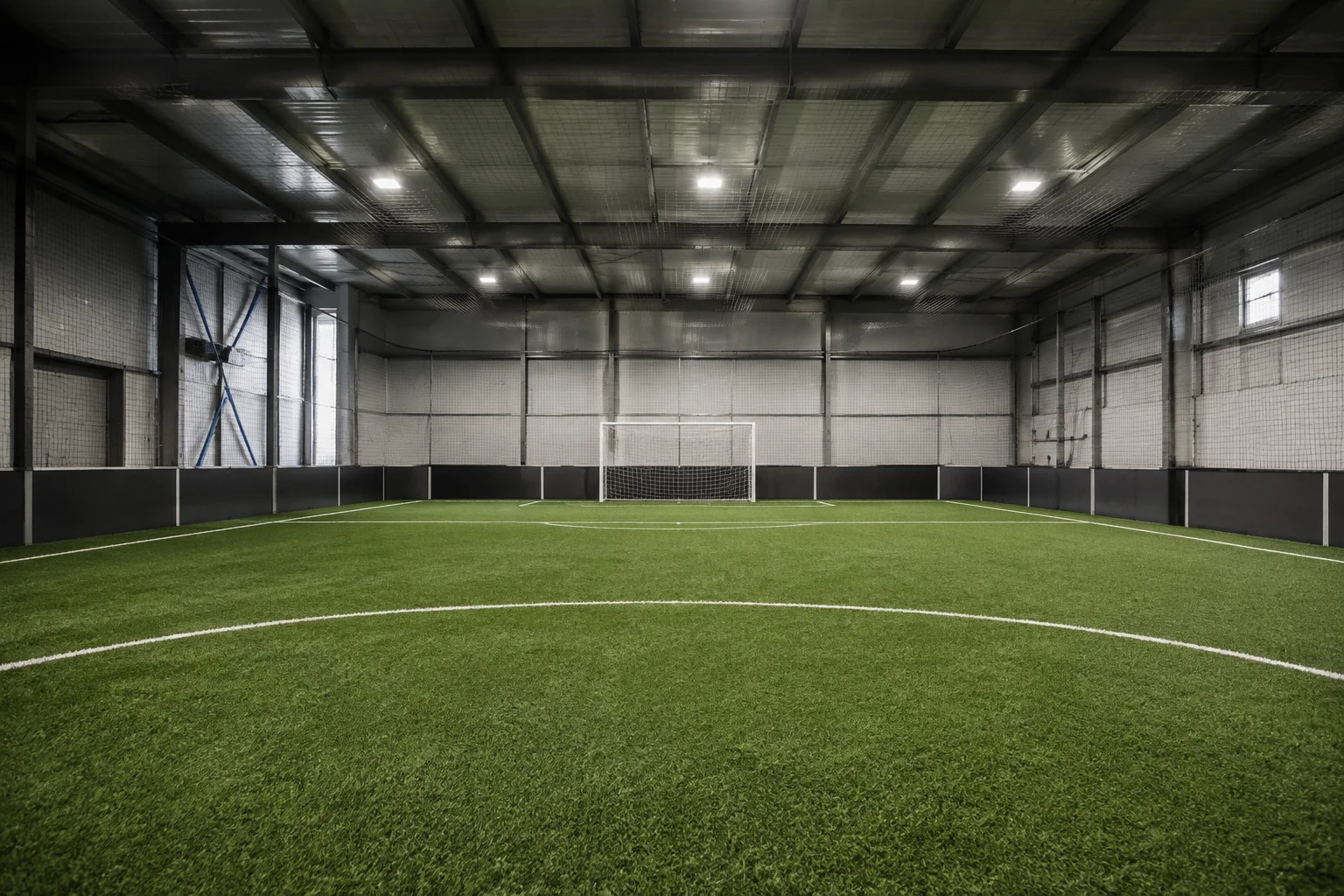 Modern indoor soccer pitch with artificial turf and perimeter netting