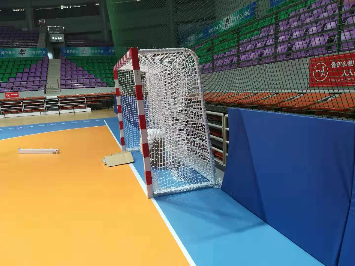 An indoor goal beside a sports court Indoor goal with red-and-white posts and net beside a sports court