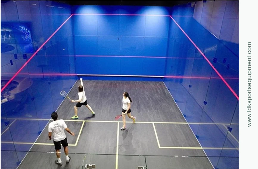 A glass-court layout brings the walls, floor and access into one playing area Players competing on a blue glass squash court