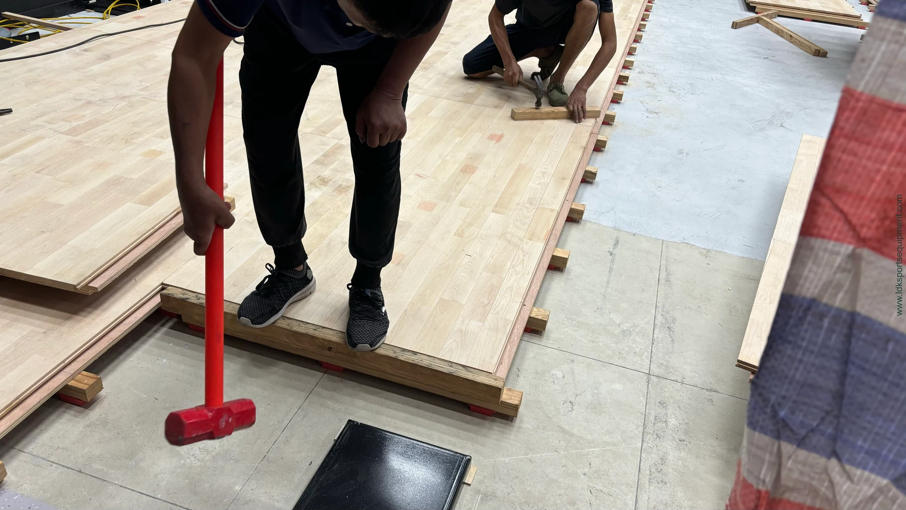 Rendering of workers fitting squash court floor panels over support components